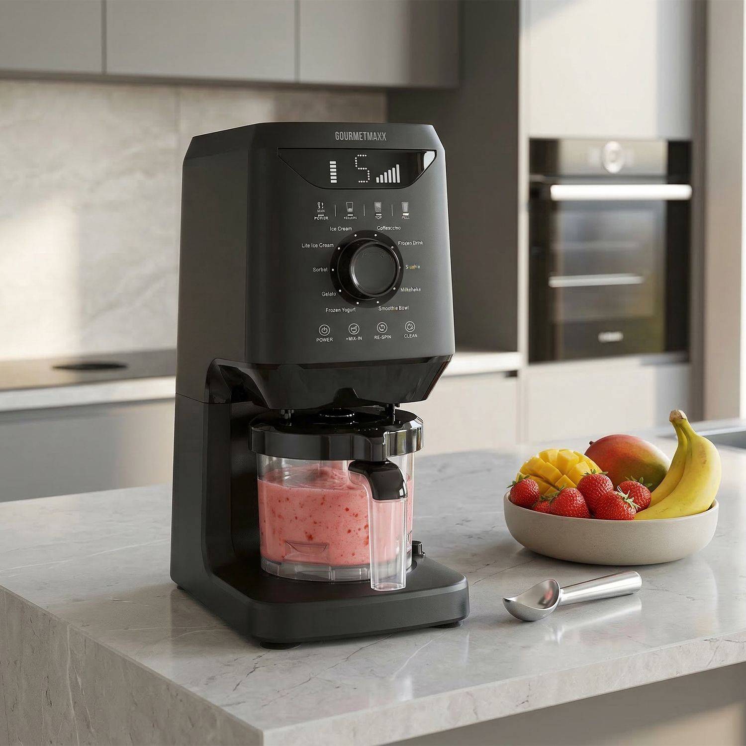 Schwarze Eismaschine mit digitalem Display und Rührbehälter mit rosa Eiscreme auf Küchenarbeitsplatte neben Schale mit Früchten und Eislöffel