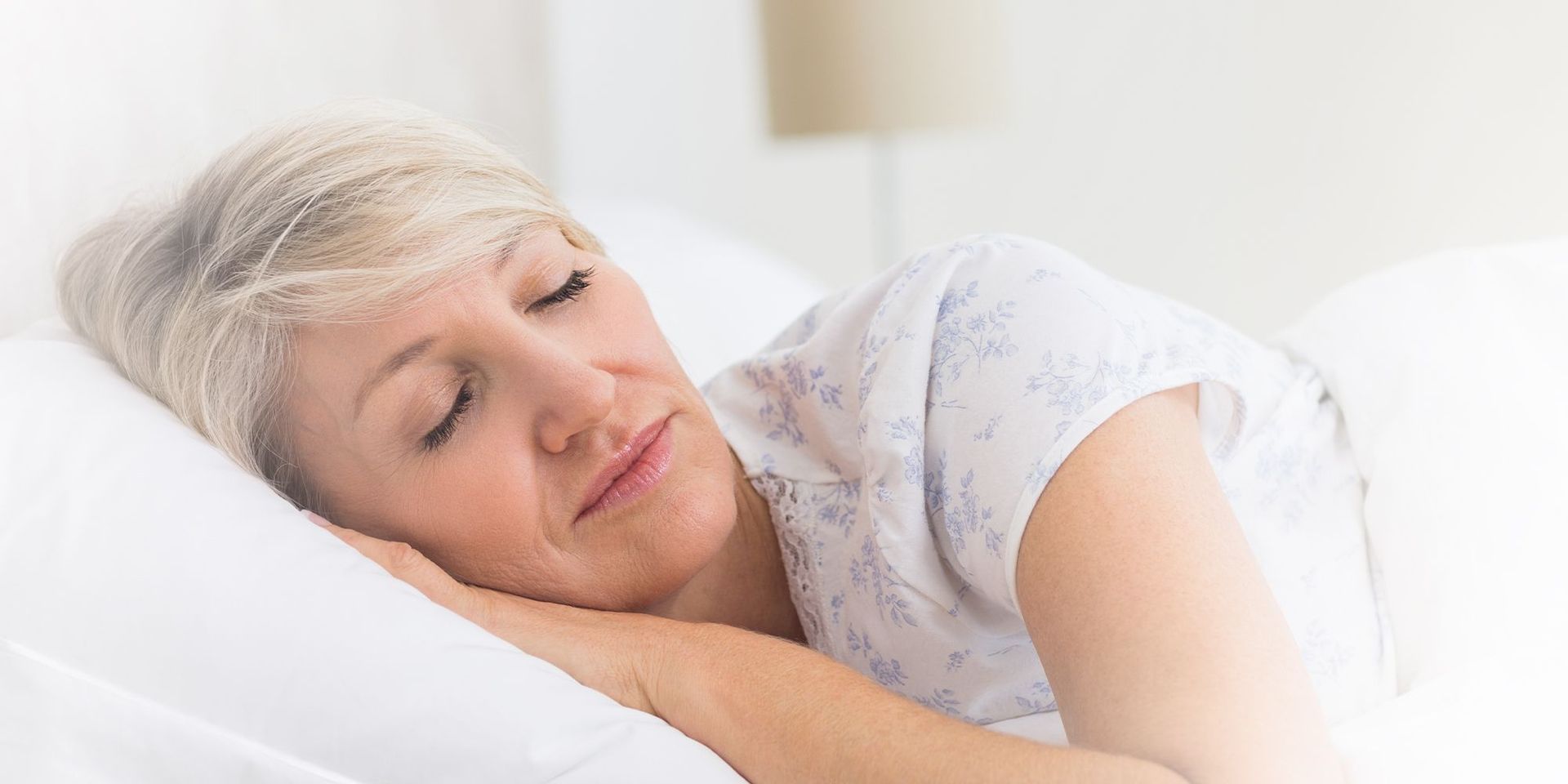 Frau schläft friedlich auf weißem Kissen in hellem Schlafzimmer