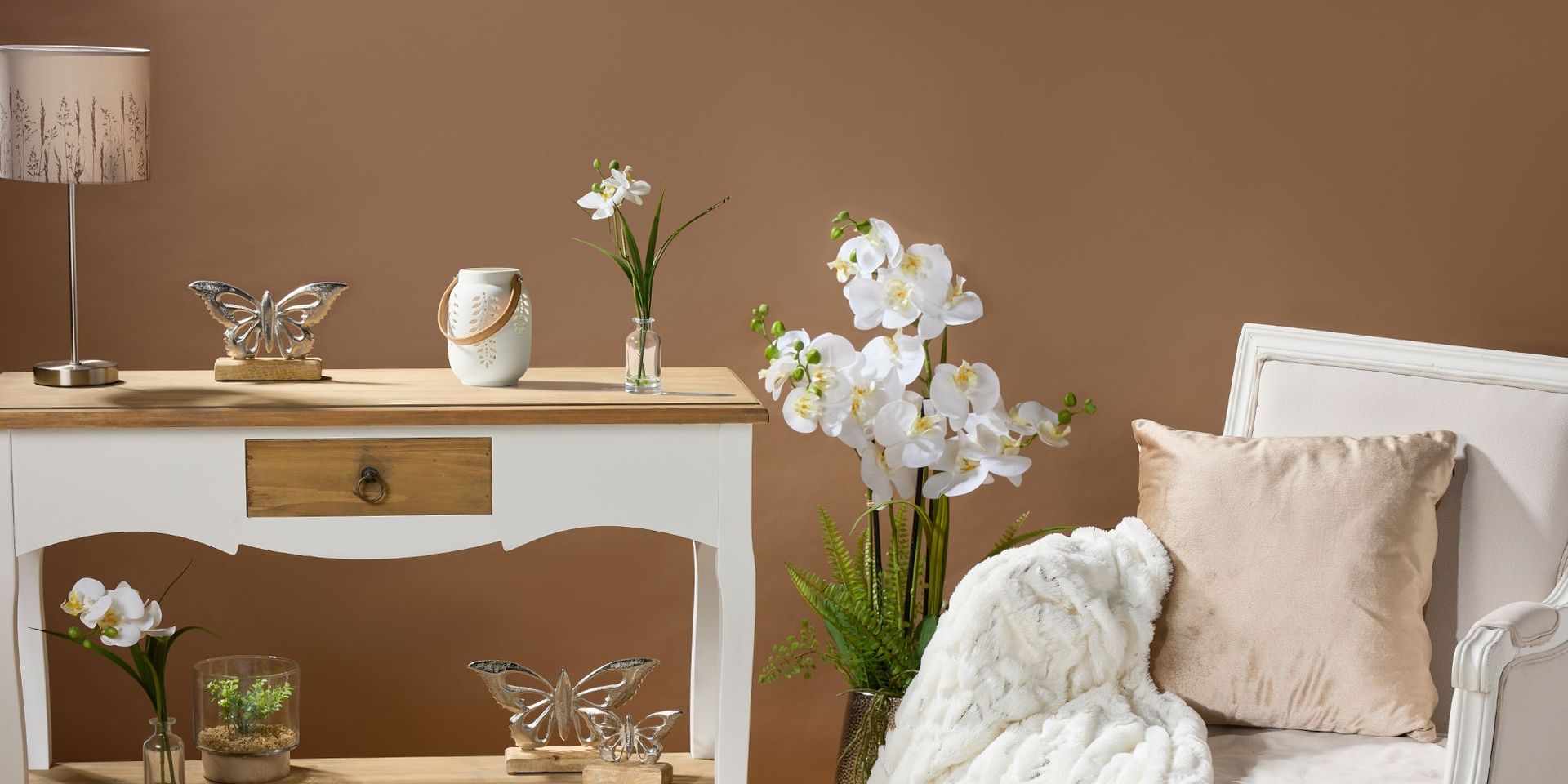 Weißes Sideboard mit Schmetterlingsdekorationen und Blumenvasen auf braunem Hintergrund