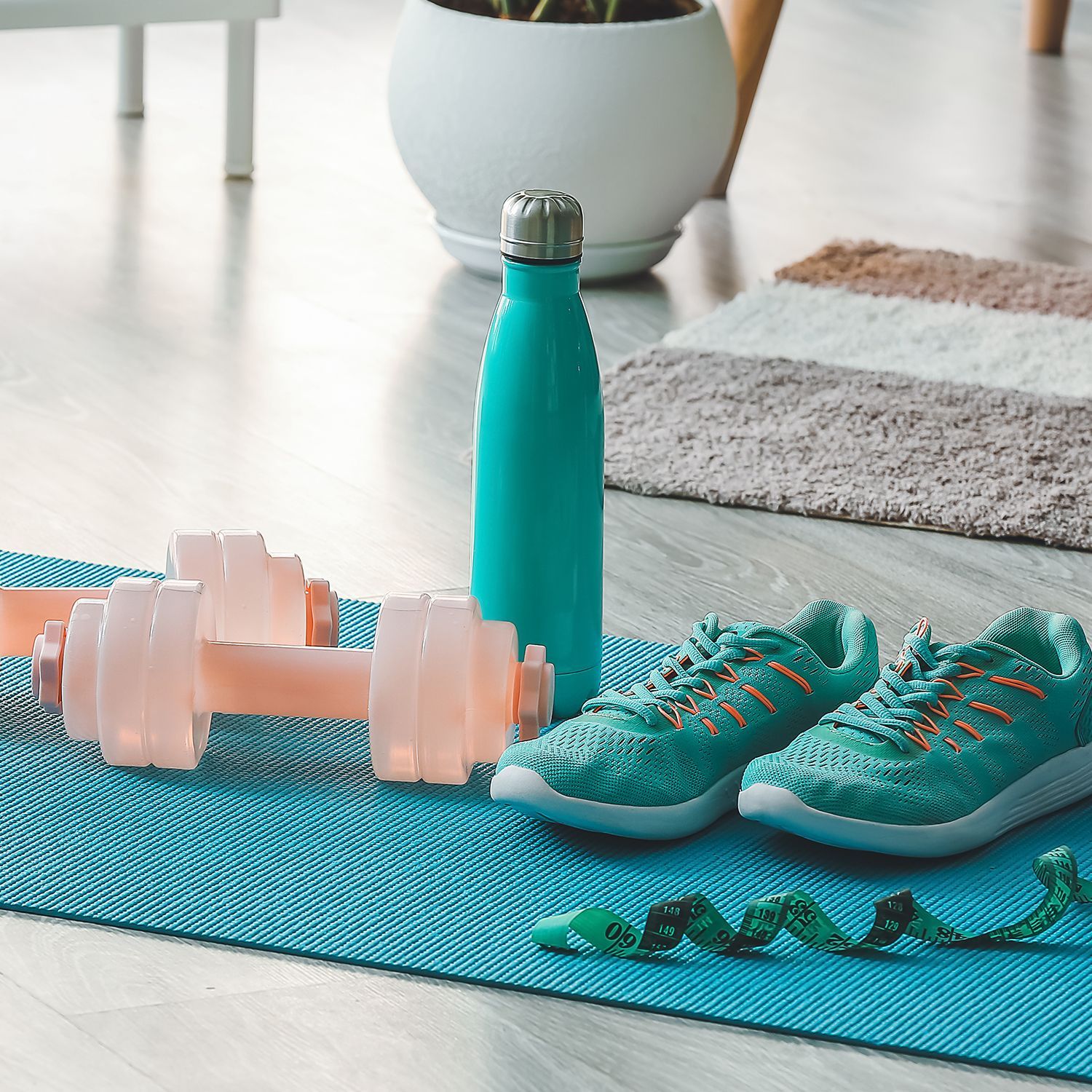 Yoga-Matte, Hanteln, Sportschuhe und Flasche Wasser in einem Wohnzimmer