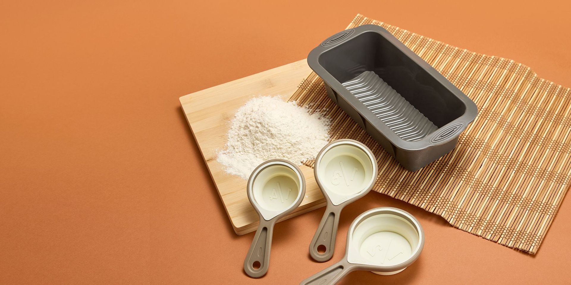 Backzubehör mit Silikonformen platziert auf einem Holzbrett