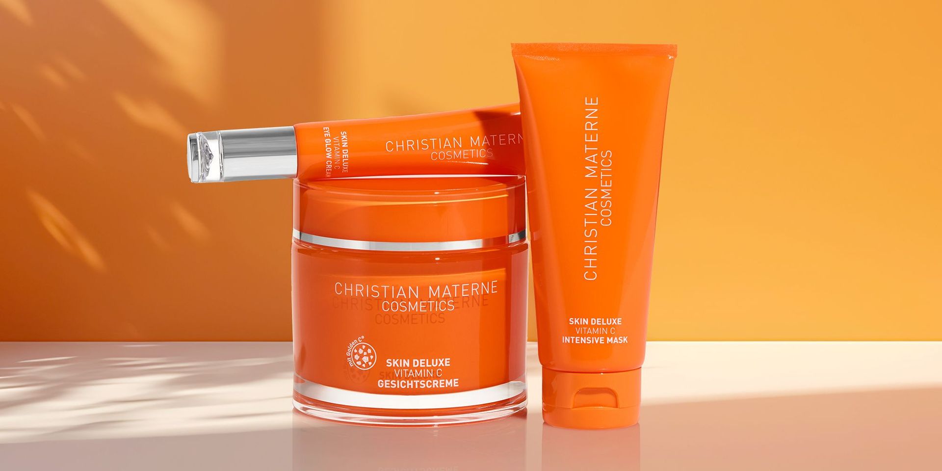 Drei orangefarbene Hautpflegeprodukte von Christian Materne Cosmetics mit Vitamin C, darunter Gesichtscreme, Intensivmaske und Serum