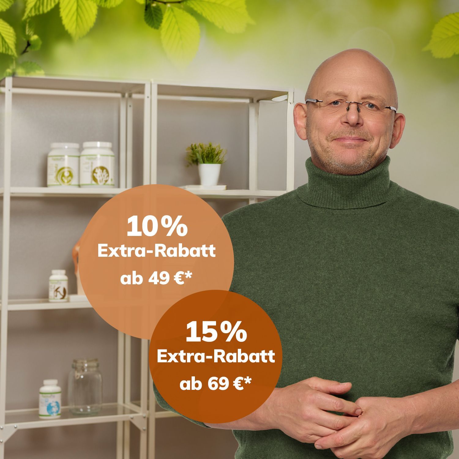 Mann mit grünem Rollkragenpullover steht vor Regal mit Pflanzen und medizinischen Modellen, Hände vor dem Bauch verschränkt.