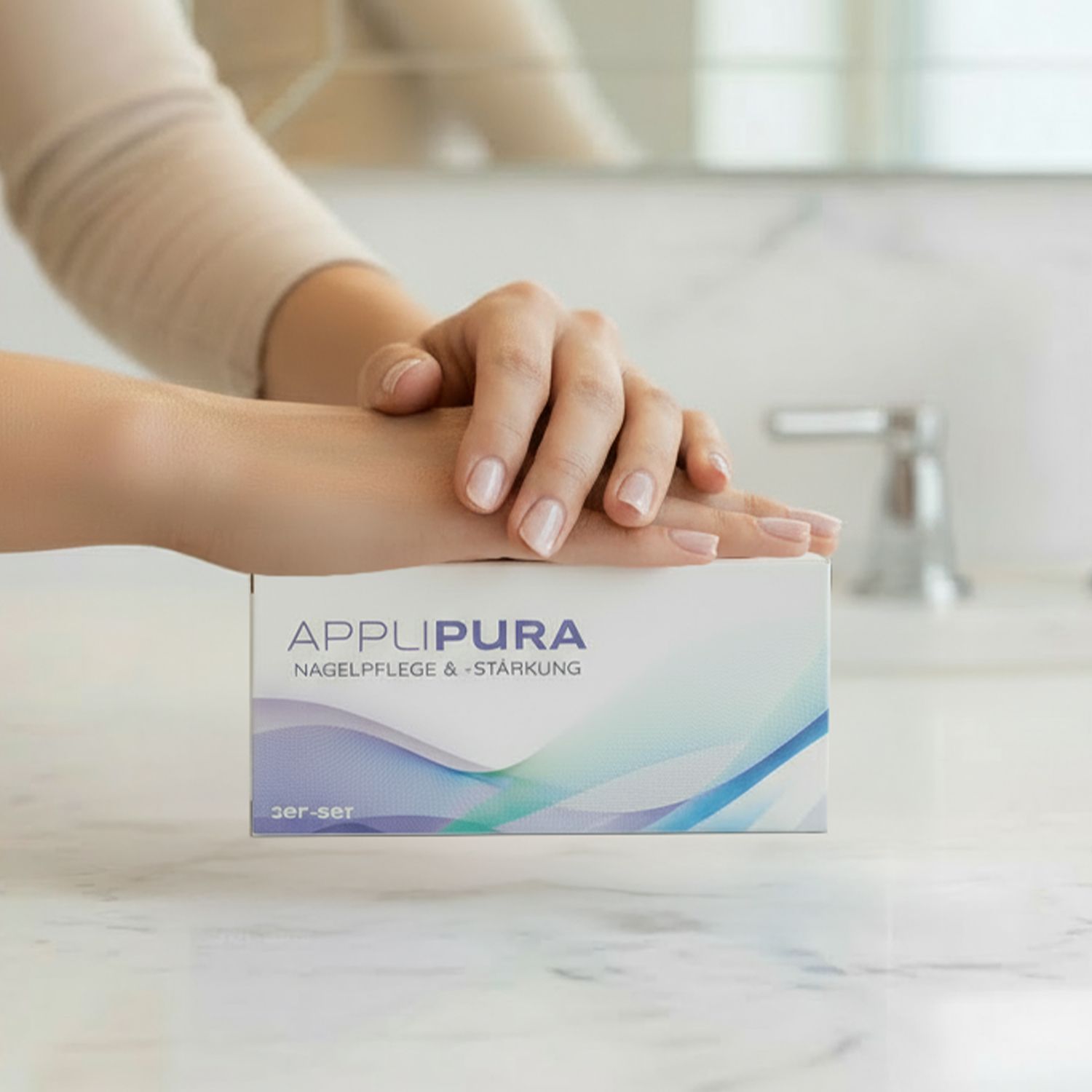 Hände auf einer weißen Verpackung mit der Aufschrift 'APPLI PURA NAGELPFLEGE & -STÄRKUNG' und farbigen Wellenmustern.