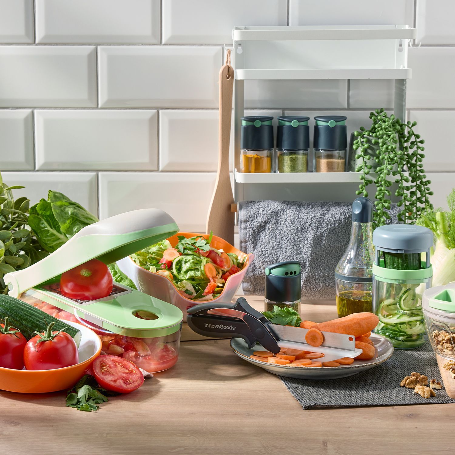 Küchenhelfer mit Gemüseschneider, Schneidebrett, frischem Gemüse und Gewürzgläsern auf Arbeitsfläche.