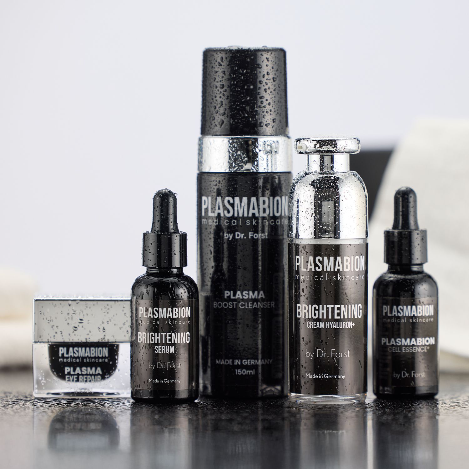 Mehrere schwarze und silberne Kosmetikflaschen und -tiegel der Marke Plasmabion auf weißem Untergrund