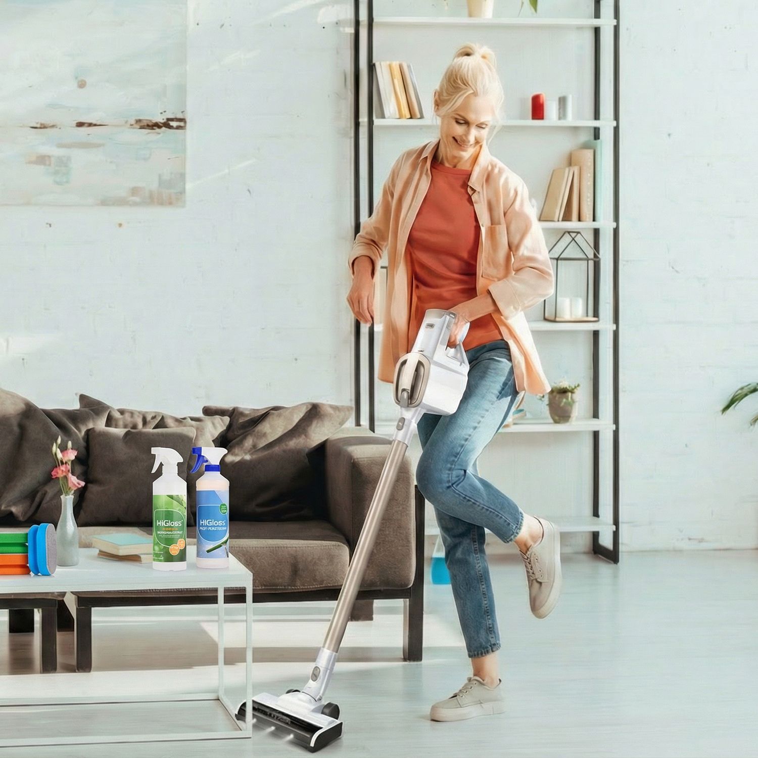 Frau mit Staubsauger in modern eingerichteter Wohnung mit Sofa, Couchtisch und Regal im Hintergrund