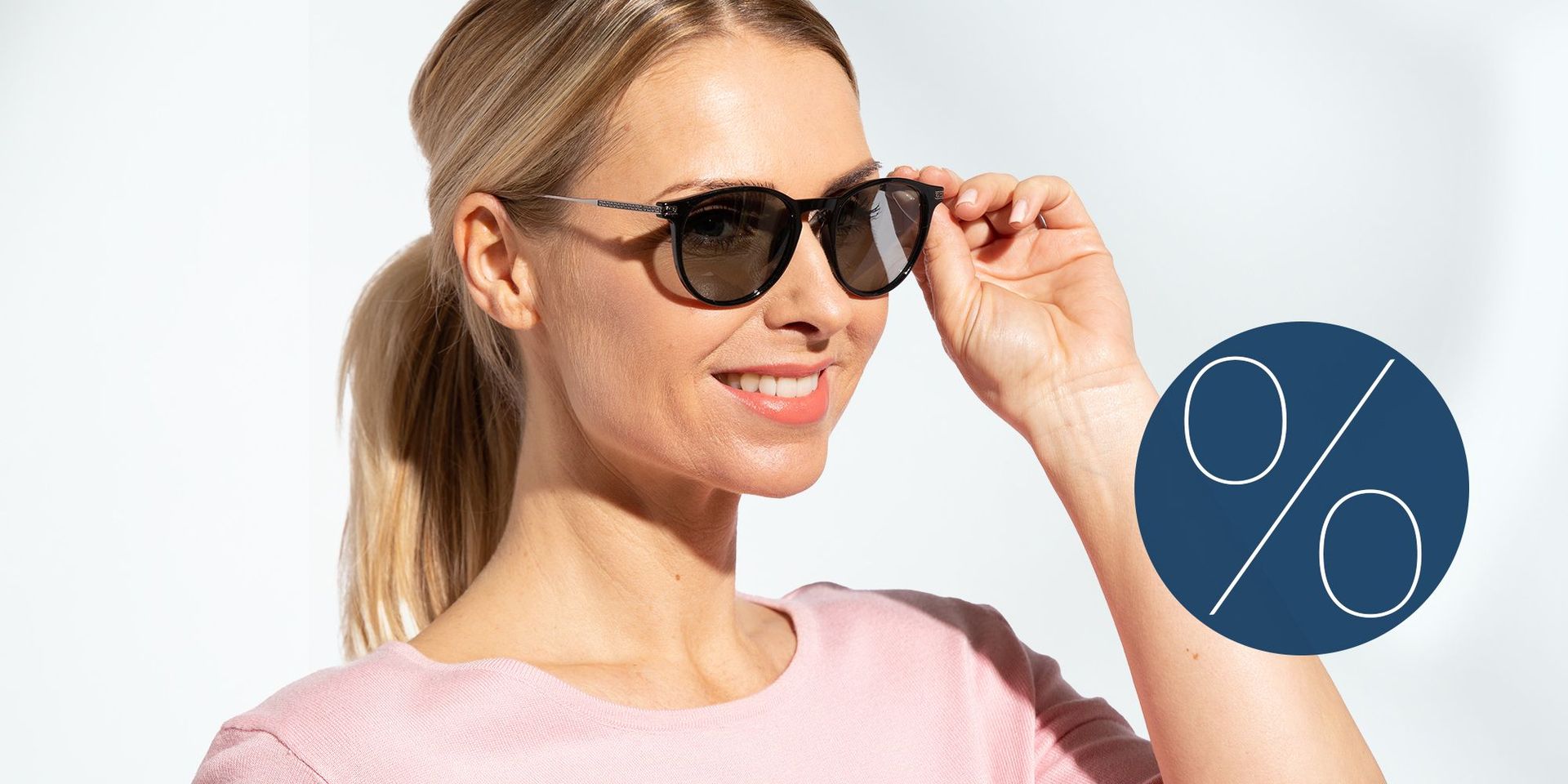 Frau mit hellblondem Pferdeschwanz, rosa Oberteil und Sonnenbrille neben einem blauen Kreis mit großem, weißen Prozentzeichen