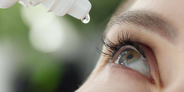 Tipps zur Pflege der Augen im Herbst Frau benetzt ihr rechtes Auge mit Augentropfen