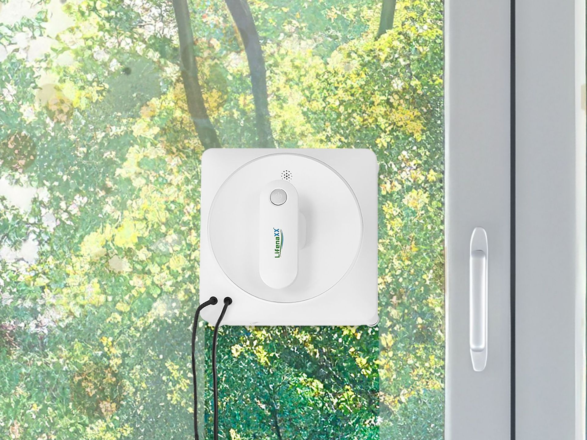 Fenster Fee Fensterputzroboter an einer Glas-Schiebetür mit grünem Laub im Hintergrund