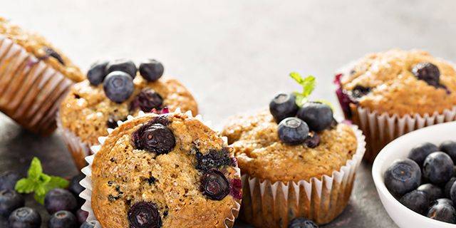 Heidelbeer-Muffins Vier Heidelbeer-Muffins mit frischen Heidelbeeren und Minzblättern auf hellem Untergrund