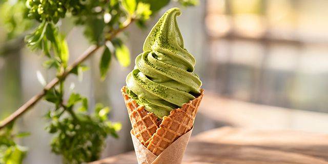 Matcha Softeis Weiches Matcha-Eis in einer Waffel mit grünem Blatt im unscharfen Hintergrund