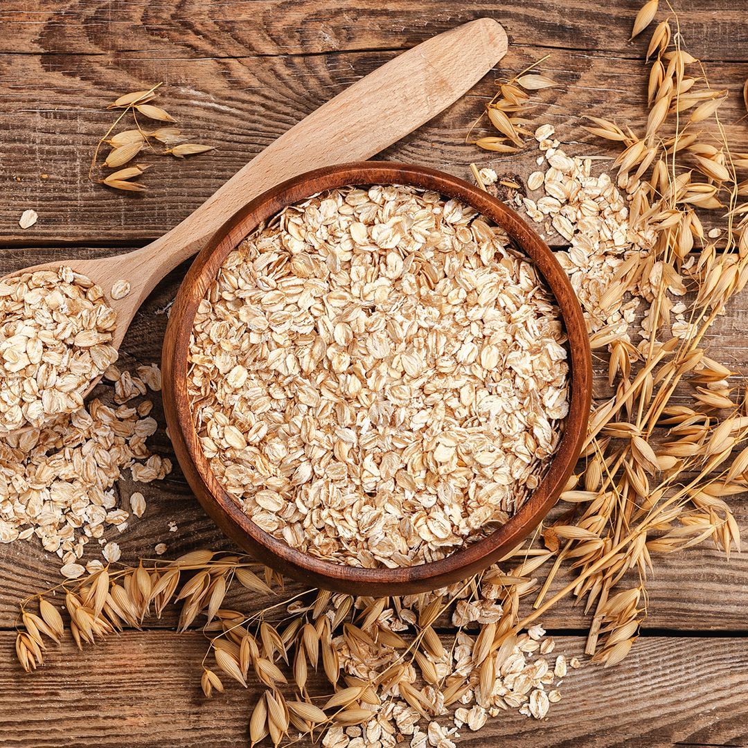 Haferflocken Holzschale mit Haferflocken auf Holztisch neben Haferähren und Holzlöffel
