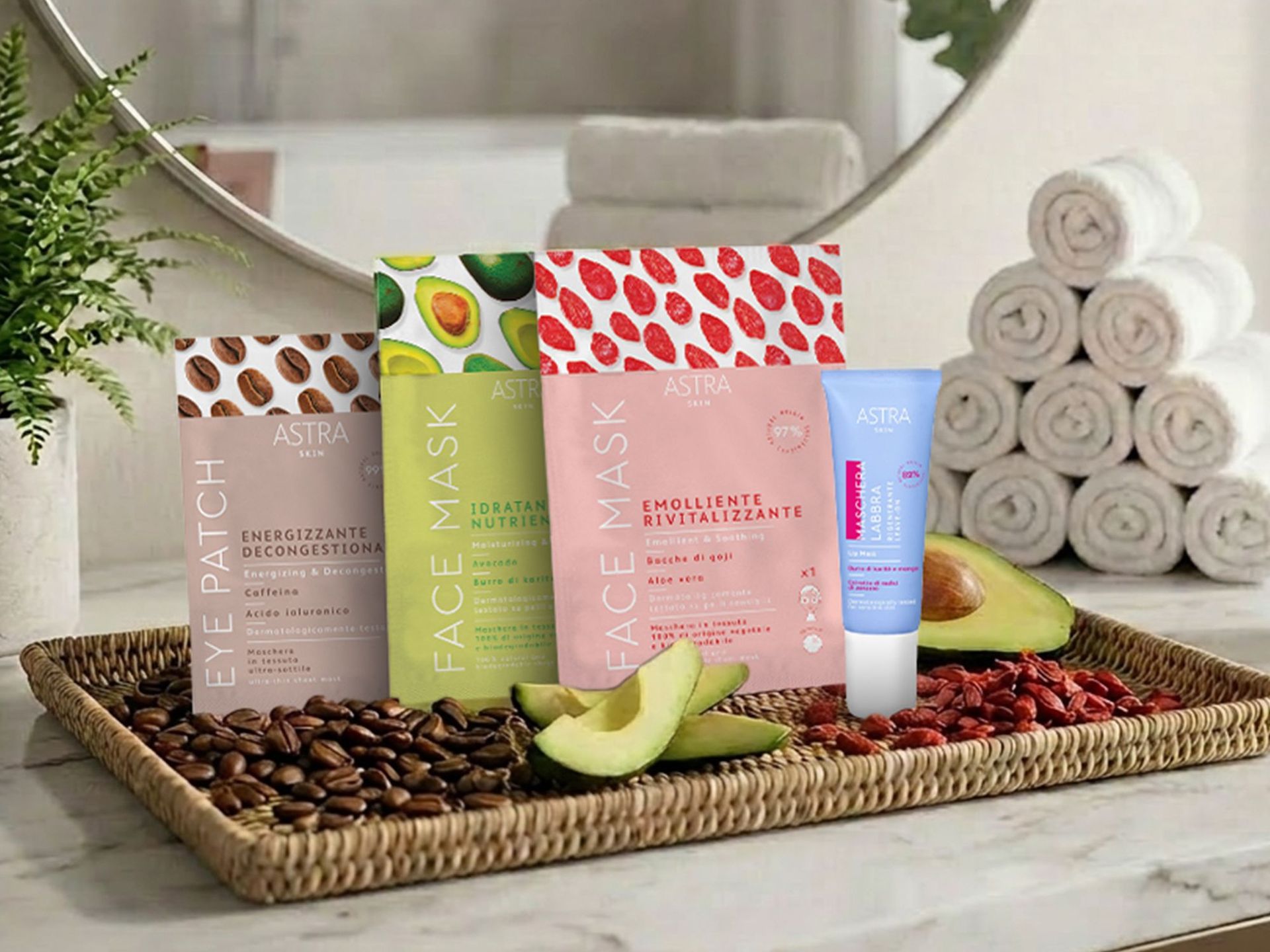 Entdecken Sie unsere Neuheiten von ASTRA für Ihren Extra-Wohlfühlmoment zu Hause! Vier verschiedene Artikel der Marke ASTRA sowie Kaffeebohnen, Avocado und Goji-Beeren in einem geflochtenen Korb auf einer Marmoroberfläche vor einem runden Spiegel und einem Stapel gerollter Handtücher